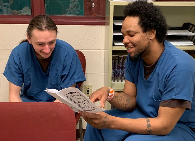 Ben and Cory, dads in the Dane County Jail and Parenting Inside Out students read pamphlet together