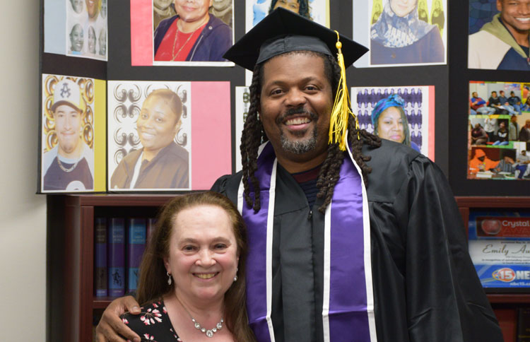 Corey in his graduation cap and gown poses with Emily