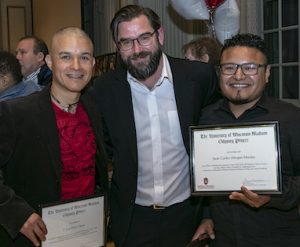 UW Odyssey instructor Kevin Mullen stands smiling between two students, Luis and Juan Carlos. Both students are holding Odyssey diplomas and smiling.