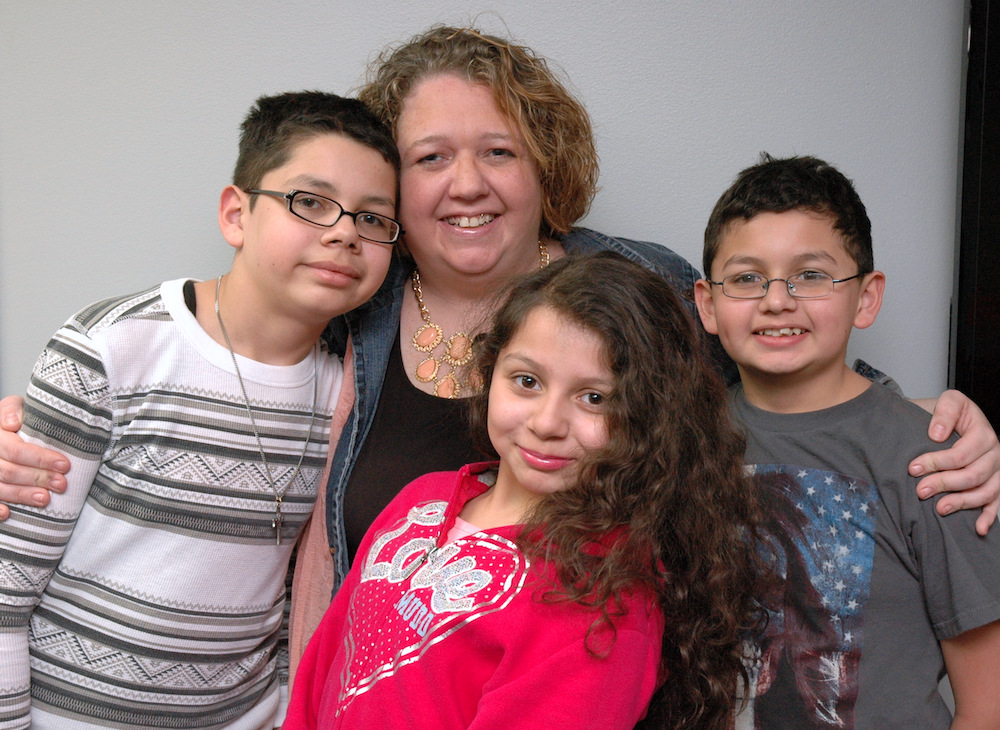 Three UW–Madison Odyssey Junior students. A woman stands behind them. All are smiling.