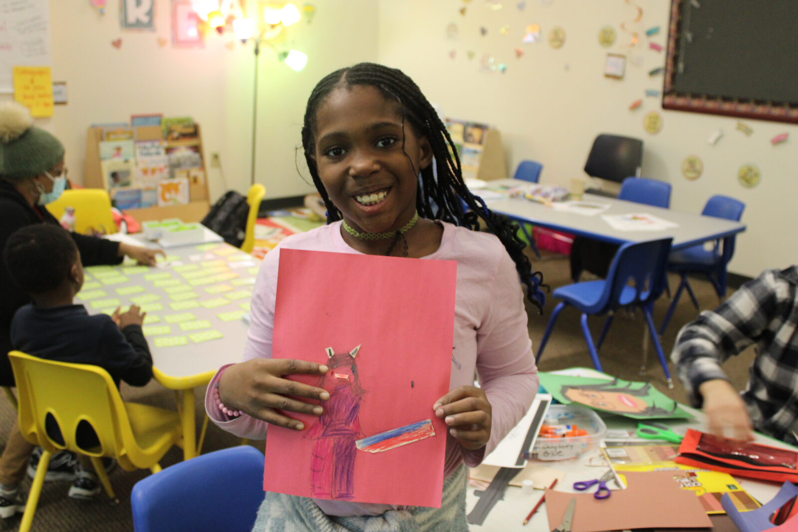Odyssey student smiling and holding a craft project